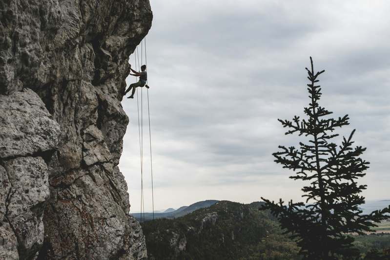 Close-up of climber placing a nut into a rock crack with harness and helmet visible