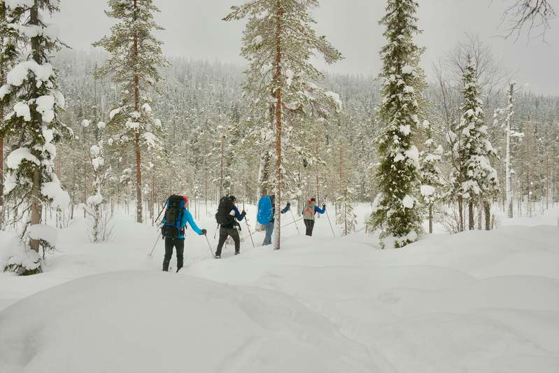 Team members smiling while preparing gear for a snowshoeing expedition